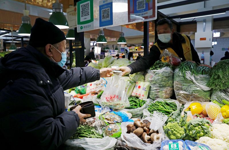 © Reuters. FILE PHOTO: People wearing face masks shop at a market, following new cases of the coronavirus disease (COVID-19) in the country, in Beijing, China January 11, 2021. REUTERS/Tingshu Wang