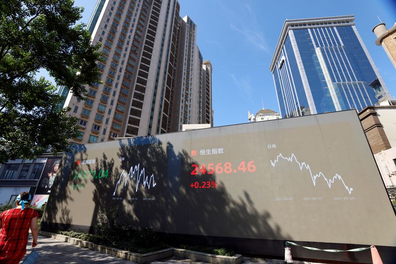 &copy; Reuters. FILE PHOTO: A woman walks by an electronic display showing the Shenzhen and Hang Seng stock indexes, in Shanghai, China, September 24, 2021. REUTERS/Aly Song