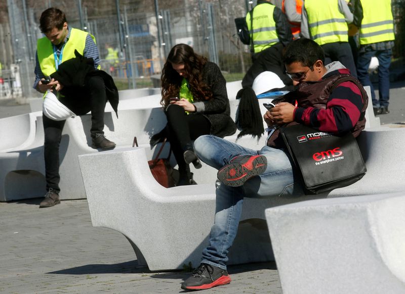 &copy; Reuters. FILE PHOTO: People use their mobile phones near the entrance to Mobile World Congress in Barcelona February 22, 2014. REUTERS/Albert Gea 
