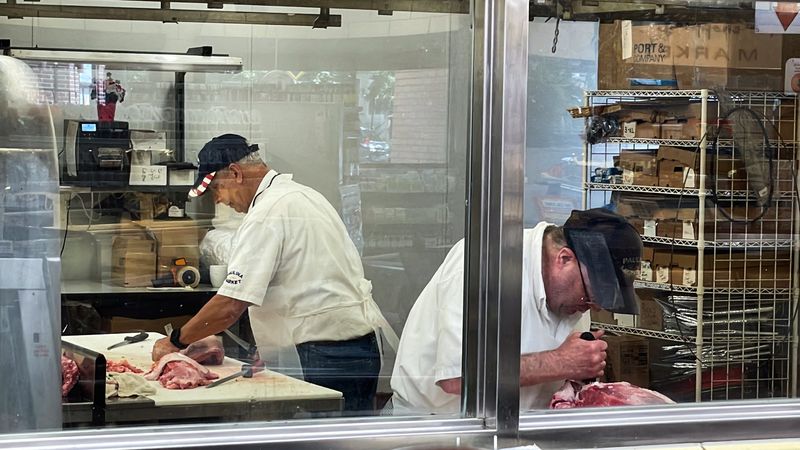 &copy; Reuters. Owner, William Begale, and one of his employees cut meat in the butcher's cutting room at Paulina Meat Market in Chicago, Illinois, U.S., June 28, 2022. REUTERS/Bianca Flowers