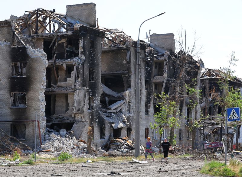 &copy; Reuters. Local residents walk past apartment buildings destroyed during Ukraine-Russia conflict in the city of Sievierodonetsk in the Luhansk Region, Ukraine June 30, 2022. REUTERS/Alexander Ermochenko