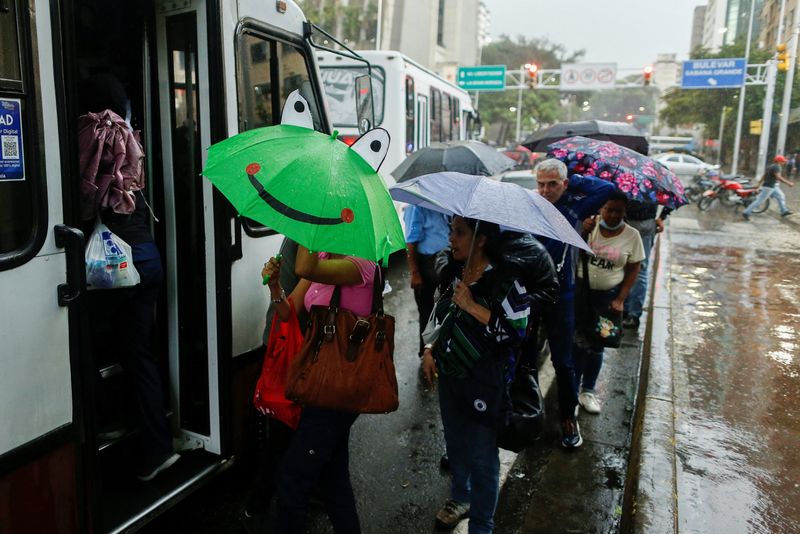 &copy; Reuters. FILE PHOTO: People in a line to board a bus use umbrellas to cover from the rain caused by Potential Tropical Cyclone Two, which the U.S. National Hurricane Center says will likely develop into tropical storm Bonnie, as it passes through the Caribbean, in