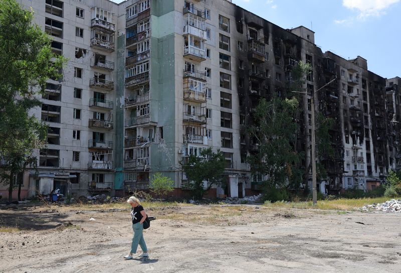 &copy; Reuters. إحدى السكان المحليين تمر بجوار مبنى سكني لحقت به أضرار شديدة خلال الصراع الأوكراني الروسي في مدينة سيفيرودونيتسك في إقليم لوجانسك بأوكراني