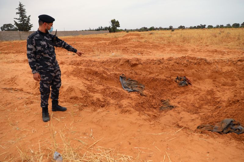 &copy; Reuters. Un membre des forces de sécurité loyales au gouvernement libyen internationalement reconnu montre une fosse commune, dans la ville de Tarhouna, en Libye. Des fosses communes, possiblement au nombre d'une centaine, restent à mettre au jour à Tarhouna, 
