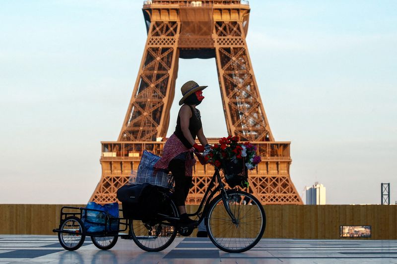 &copy; Reuters. Imagen de archivo de una mujer con mascarilla montando una bicicleta cerca de la torre Eiffel, en la plaza del Trocadero de París, durante el toque de queda nacional, de 19 a 6 horas, debido al endurecimiento de las medidas contra la propagación del COV