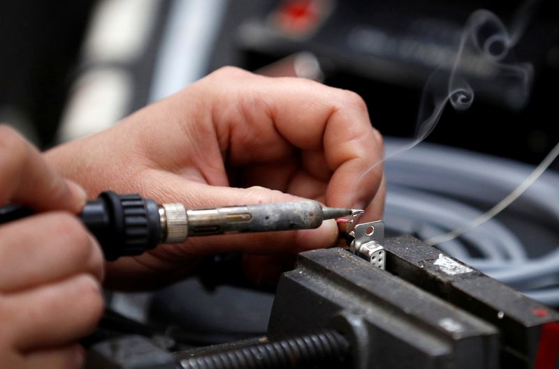 © Reuters. FILE PHOTO: A worker solders electrical wire to a component on the factory floor of PP Control and Automation near Cannock, Britain, July 6, 2016. REUTERS/Phil Noble