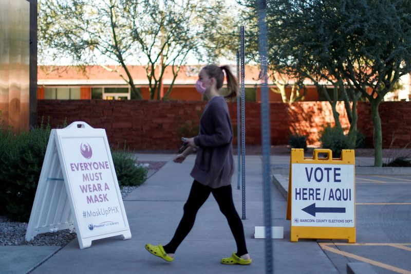 © Reuters. FILE PHOTO: A woman walks to cast her ballot at the register of voters during early voting in Phoenix, Arizona, U.S., October 29, 2020. REUTERS/Edgard Garrido/File Photo