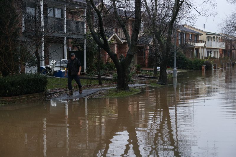 &copy; Reuters. Ewan Thomas walks past floodwaters inundating a residential area, following heavy rains and severe flooding in the McGraths Hill suburb of Sydney, Australia, July 6, 2022.  REUTERS/Loren Elliott