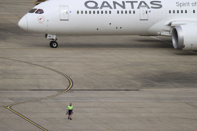 © Reuters. FILE PHOTO: A ground worker walking near a Qantas plane is seen from the international terminal at Sydney Airport, in Sydney, Australia, Nov. 29, 2021. REUTERS/Loren Elliott/File Photo