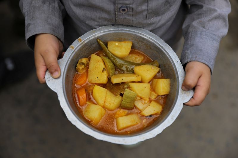&copy; Reuters. Un garçon tient un repas reçu d'une cuisine de charité pendant le mois sacré du Ramadan à Sanaa, au Yémen. La faim dans le monde a de nouveau progressé l'an dernier, alors que la guerre en Ukraine et le changement climatique, après la crise du cor