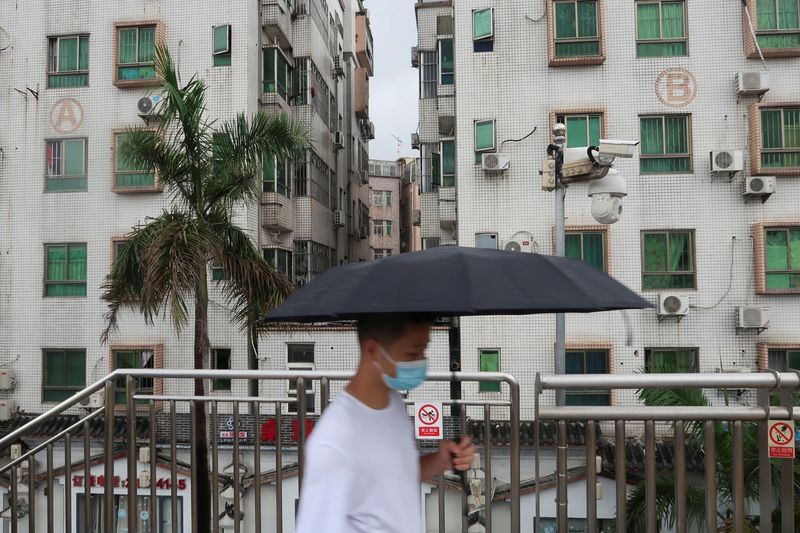 &copy; Reuters. A man holding an umbrella walks on a pedestrian bridge by surveillance cameras, near Caopu in Shenzhen's Luohu district, Guangdong province, China July 5, 2022. REUTERS/David Kirton