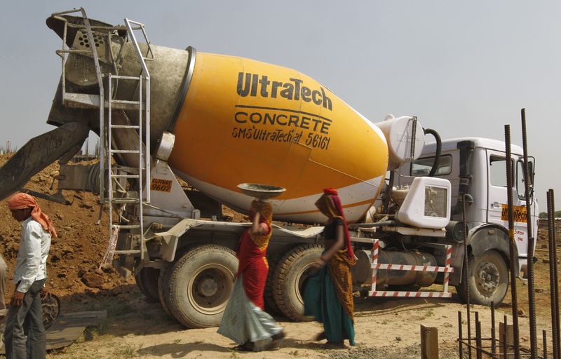 © Reuters. Workers walk in front of an UltraTech concrete mixture truck at the construction site of a commercial complex on the outskirts of the western Indian city of Ahmedabad April 22, 2013. REUTERS/Amit Dave