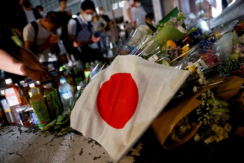 &copy; Reuters. A Japanese flag is seen as people pray next to tributes laid at the site where late former Japanese Prime Minister Shinzo Abe was shot while campaigning for a parliamentary election, near Yamato-Saidaiji station in Nara, western Japan, July 8, 2022. REUTE