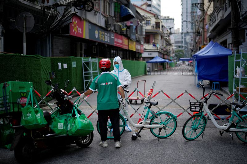 &copy; Reuters. FILE PHOTO: A worker in a protective suit gets food from a delivery worker at a closed residential area during lockdown, amid the coronavirus disease (COVID-19) outbreak, in Shanghai, China, May 25, 2022. REUTERS/Aly Song/File Photo