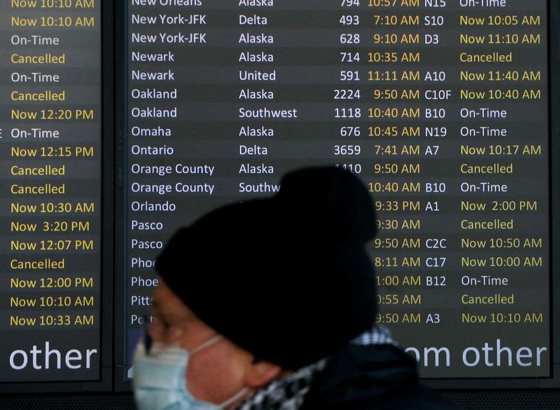 © Reuters. FILE PHOTO: A traveler walks past a screen showing dozens of flights listed as cancelled or delayed at Seattle-Tacoma International Airport (Sea-Tac) in Seattle, Washington, U.S. December 27, 2021.  REUTERS/Lindsey Wasson