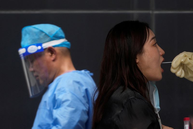 © Reuters. A woman gets tested for COVID-19 on a street, amid new lockdown measures in parts of the city to curb the coronavirus disease (COVID-19) outbreak in Shanghai, China July 11, 2022. REUTERS/Aly Song