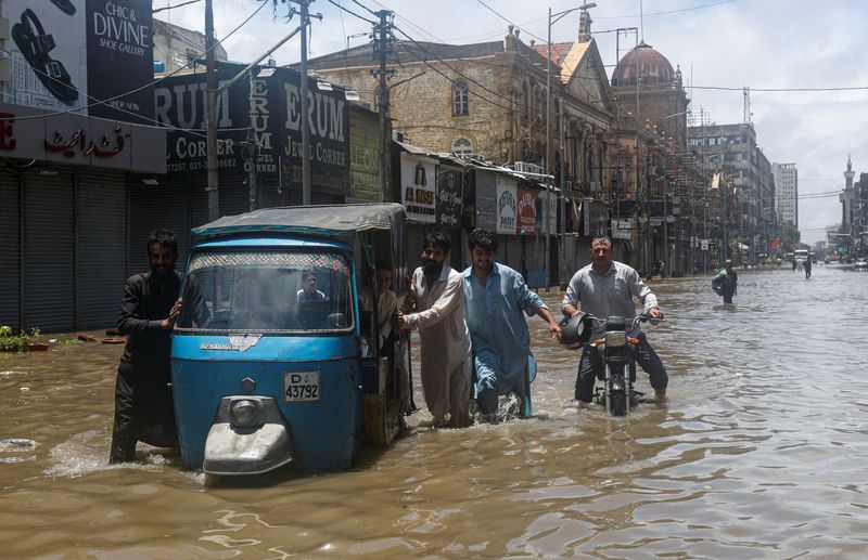 &copy; Reuters. رجال يخوضون في مياه الأمطار في كراتشي يوم الاثنين. تصوير: أخطر سومرو - رويترز.
