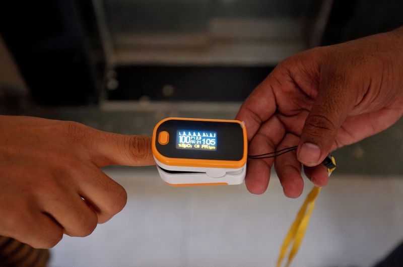 &copy; Reuters. IMAGEN DE ARCHIVO. Un trabajador médico coloca un oxímetro de pulso en el dedo de una mujer para verificar su nivel de oxígeno durante una encuesta puerta a puerta para detectar la enfermedad del coronavirus en medio de su propagación en Ahmedabad, In