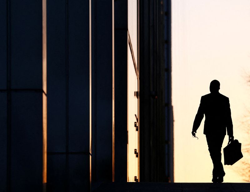 &copy; Reuters. FILE PHOTO: A worker arrives at his office in the Canary Wharf business district in London Feb. 26, 2014.