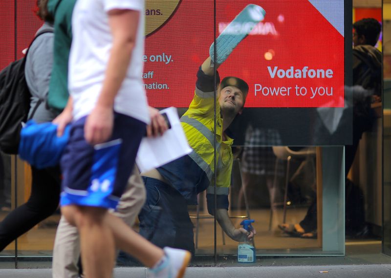© Reuters. FILE PHOTO: A worker cleans the window of a telecommunications retail store in central Sydney, Australia, June 16, 2017. REUTERS/Steven Saphore