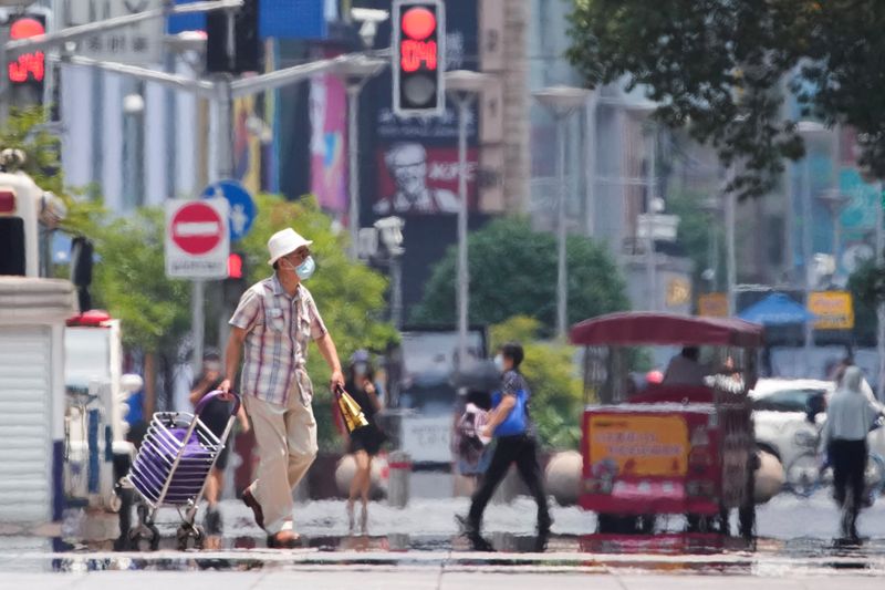 &copy; Reuters. FOTO DE ARCHIVO: Un hombre con mascarilla camina por una calle con un carrito de la compra durante una ola de calor en Shanghái, China, el 13 de julio de 2022. REUTERS/Aly Song