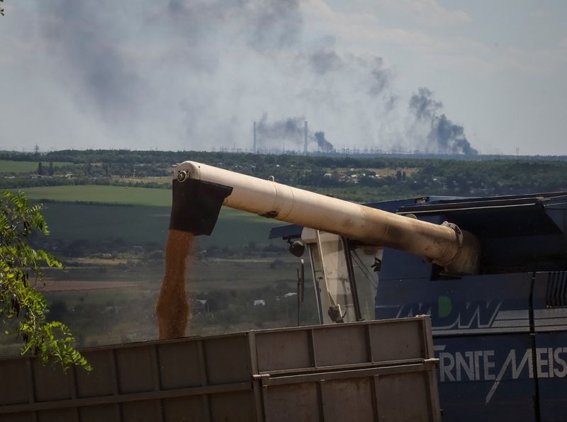 &copy; Reuters. Agricultores colhem trigo na região ucraniana de Donbas enquanto usina de energia queima ao fundo, após ataque de artilharia durante invasão russa na Ucrânia
13/07/2022 REUTERS/Gleb Garanich