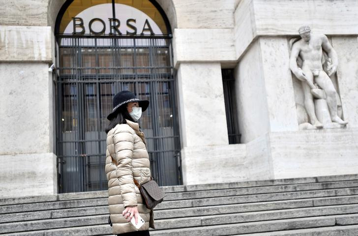 &copy; Reuters. IMAGEN DE ARCHIVO. Una mujer utilizando mascarilla se ve frente a la Bolsa de Valores de Milán, Italia