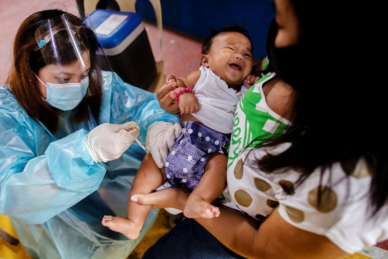 &copy; Reuters. FILE PHOTO: A nurse wearing personal protective equipment (PPE) for protection against the coronavirus disease (COVID-19) gives routine vaccines to a baby held by his mother in a local health center in Manila, Philippines January 27, 2021. REUTERS/Eloisa 