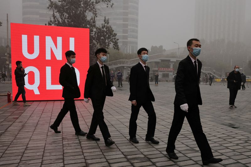 &copy; Reuters. FILE PHOTO: Security staff enter a store of the Uniqlo fast fashion retailer before its opening in the Sanlitun shopping district on a polluted day in Beijing, China, November 6, 2021. REUTERS/Thomas Peter