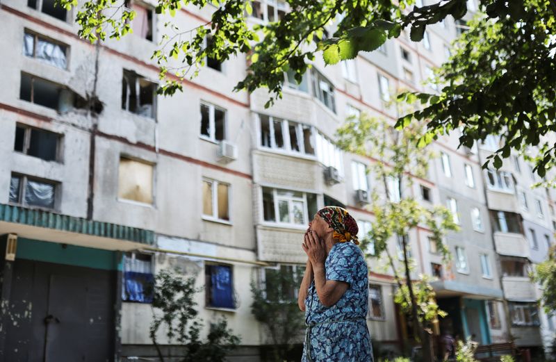 &copy; Reuters. سيدة تقف أمام مبنى لحقته أضرار في أعقاب ضربة عسكرية في خاركيف بأوكرانيا يوم الجمعة. تصوير: ناتشو دوس - رويترز 