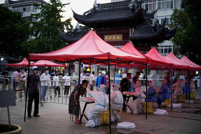 &copy; Reuters. Des personnes font la queue pour subir un test de dépistage du coronavirus (COVID-19) dans un site de test d'acide nucléique, à Shanghai. Plusieurs grandes villes chinoises dont Shanghai sont sur le qui-vive face à de nouveaux foyers de contamination 