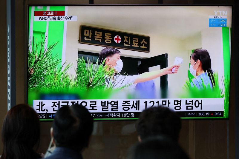 &copy; Reuters. 　北朝鮮国営の朝鮮中央通信（ＫＣＮＡ）は、国内で最初に確認された感染者に端を発した危機が「ようやく打開」に近づいていると伝えた。写真は北朝鮮の感染関連ニュースを見入る人々