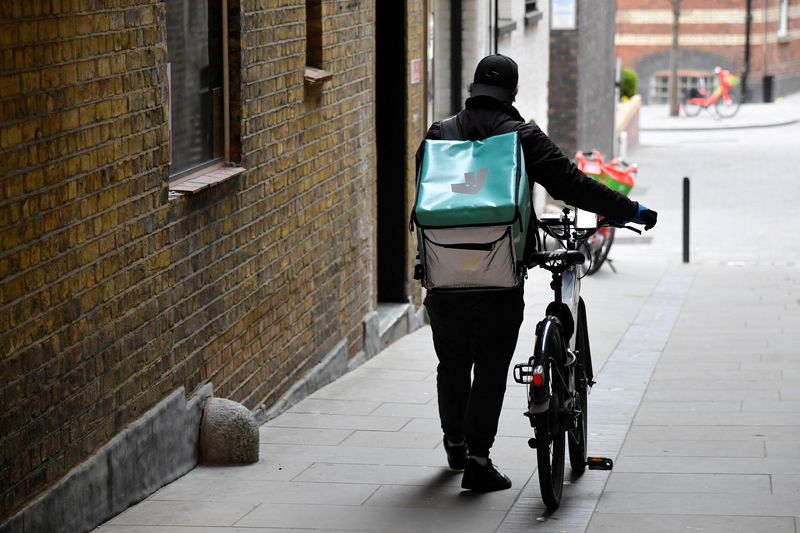 © Reuters. FILE PHOTO: A Deliveroo delivery rider pushes a bicycle in London, Britain, March 31, 2021. REUTERS/Toby Melville/File Photo