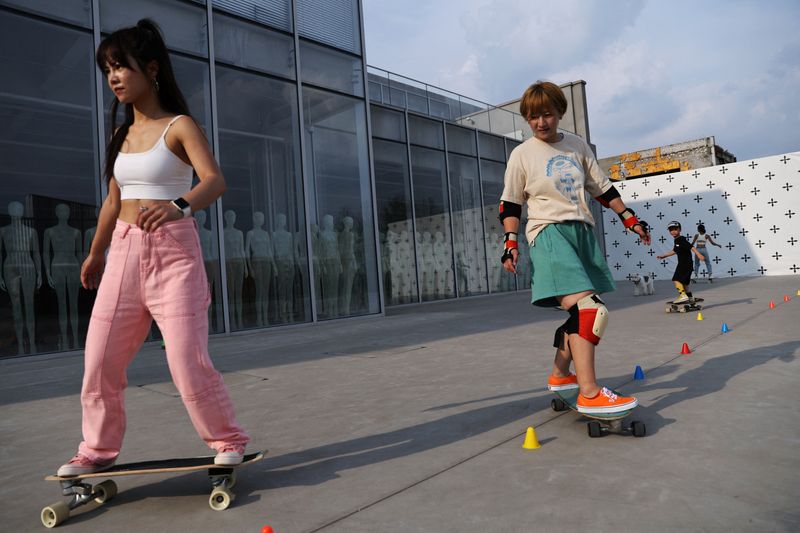&copy; Reuters. Mina Zhao, 40,  a member of Beijing Girls Surfskating Community, and other fellow members ride skateboards through a slalom cone line during a practise session, at an industrial park in Beijing, China June 30, 2022. REUTERS/Tingshu Wang     