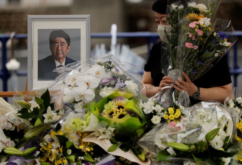 &copy; Reuters. أحد المعزين يقدم الزهور بجوار صورة رئيس الوزراء الياباني السابق الراحل شينزو آبي في مقر الحزب الليبرالي الديمقراطي بعد أسبوع من اغتياله في 