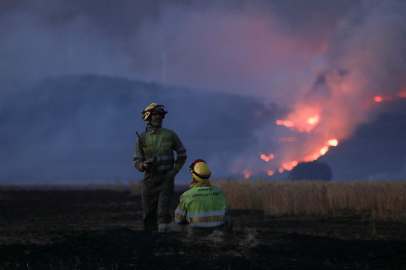 &copy; Reuters. رجلا إطفاء يلتقاطان أنفاسهما بجوار حريق مشتغل بالغابات في إسبانيا يوم 18 يوليو تموز 2022. رويترز