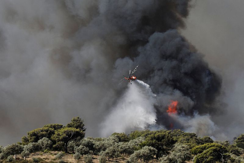 © Reuters. A firefighting helicopter makes a water drop as a wildfire burns in the Pikermi suburb of Athens, Greece, July 20, 2022. REUTERS/Louiza Vradi