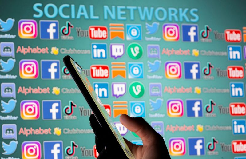 © Reuters. FILE PHOTO: Woman with smartphone is seen in front of displayed social media logos in this illustration taken, May 25, 2021. REUTERS/Dado Ruvic/Illustration/File Photo