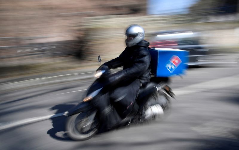 &copy; Reuters. FILE PHOTO: A Domino's pizza delivery driver rides a motorbike in a residential street in West London as the spread of the coronavirus disease (COVID-19) continues, in London, Britain, March 24, 2020. REUTERS/Toby Melville/File Photo  