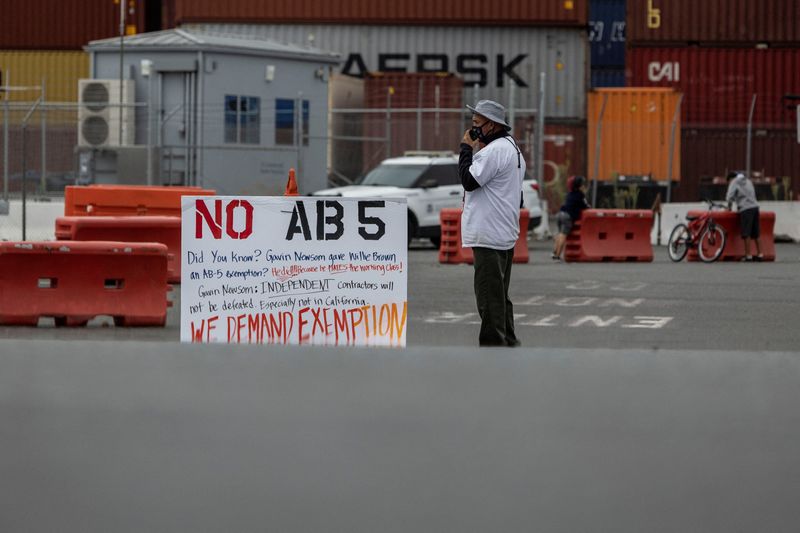 © Reuters. A truck driver joins a gathering to block the entrance of trucks at a container terminal at the Port of Oakland, during a protest against California's law known as AB5, in Oakland, California, July 21, 2022. REUTERS/Carlos Barria