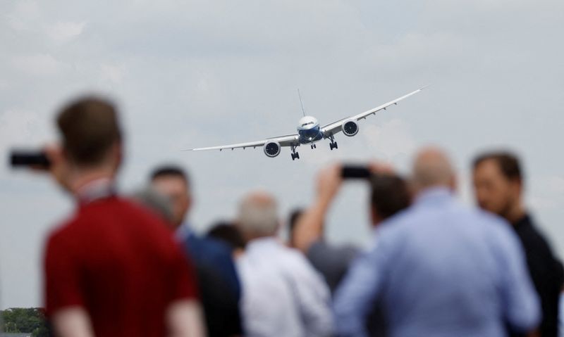 © Reuters. FILE PHOTO: Attendees watch a Boeing 777X aircraft during a display at the Farnborough International Airshow, in Farnborough, Britain, July 20, 2022.  REUTERS/Peter Cziborra/File Photo