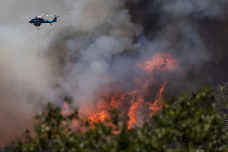 &copy; Reuters. A firefighting helicopter drops water on a hillside to control the Oak Fire as it burns near Darrah in Mariposa County, California, U.S., July 24, 2022. REUTERS/Carlos Barria 