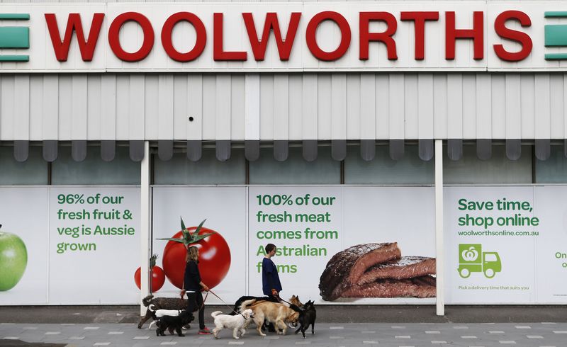 &copy; Reuters. FILE PHOTO: Women walk dogs in front of a Woolworths store in Sydney July 30, 2013. Australia's largest supermarket chain Woolworths Ltd on Tuesday reported a 4.3 percent increase in fourth-quarter total group sales year-on-year, even as food and liquor s
