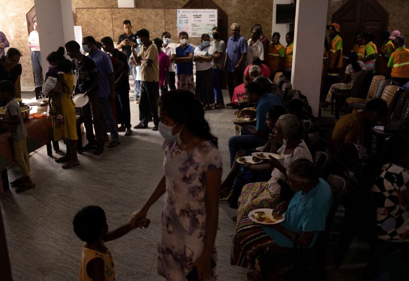 © Reuters. People eat at a community kitchen while others stand in a queue to receive food inside a church, amid the country's economic crisis, in Colombo, Sri Lanka, July 25, 2022. REUTERS/Adnan Abidi