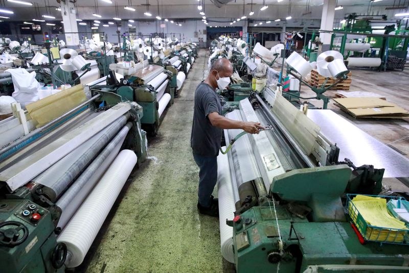 &copy; Reuters. A man works in a weaving factory, as Bangkok city administration and temples drive efforts to encourage the public to donate plastic bottles, which will be collected and upcycled into reusable Personal Protective Equipment (PPE) to reduce plastic waste as