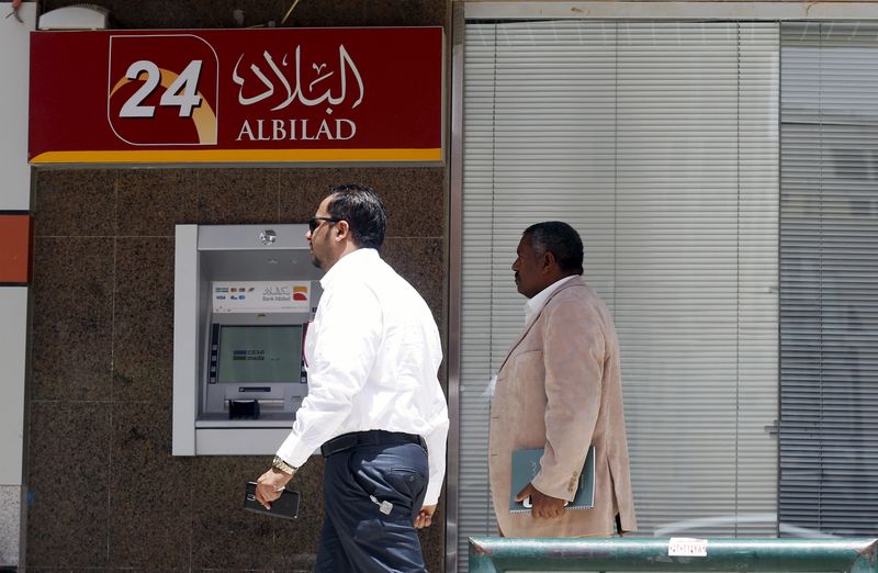 &copy; Reuters. رجلان يمران بماكينة سحب أموال تابعة لبنك البلاد السعودي بالرياض في صورة من أرشيف رويترز.