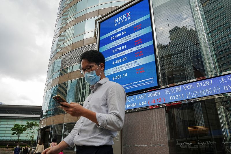 &copy; Reuters. People walk past a screen displaying the Hang Seng stock index outside Hong Kong Exchanges, in Hong Kong, China July 19, 2022. REUTERS/Lam Yik