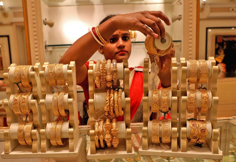 &copy; Reuters. FOTO DE ARCHIVO: Una vendedora muestra brazaletes de oro a un cliente en una sala de exposición de joyas con motivo de Akshaya Tritiya, un importante festival de compra de oro, en Calcuta, India. 3 de mayo de 2022. REUTERS/Rupak De Chowdhuri/File Photo