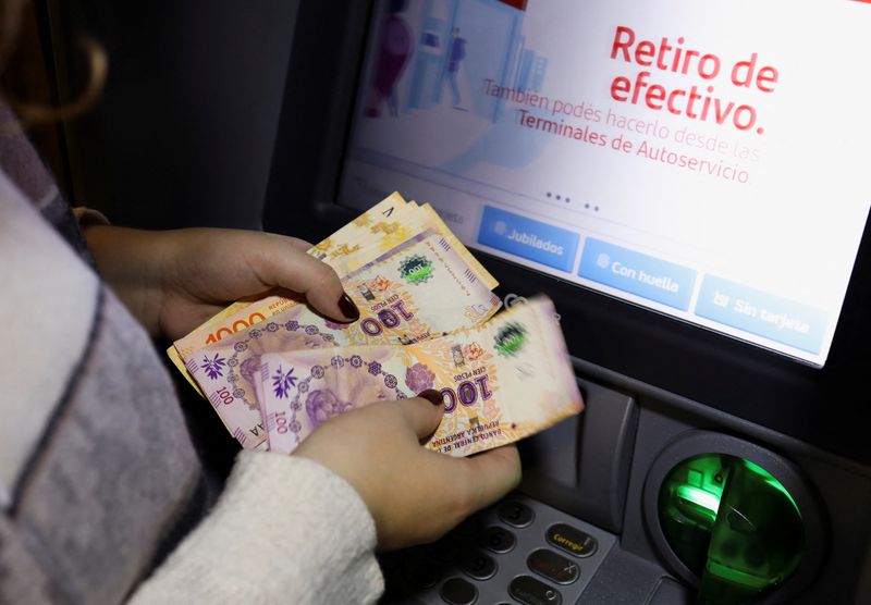 © Reuters. Pessoa conta pesos argentinos que sacou de caixa eletrônico, em Buenos Aires, Argentina 
26/07/2022
REUTERS/Cristina Sille