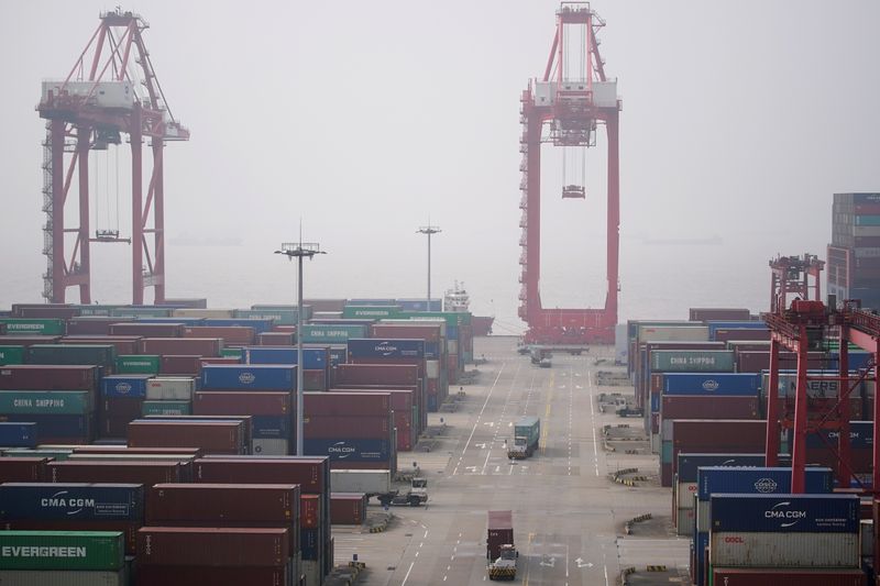 &copy; Reuters. Trucks travel past containers at the Yangshan Deep Water Port in Shanghai, China January 13, 2022. Picture taken January 13, 2022. REUTERS/Aly Song